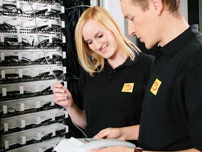 Elektriker*innen arbeiten an einem Netzwerkschrank